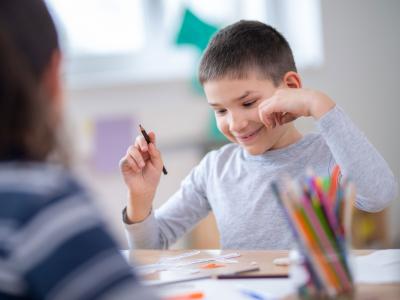 A young person smiles while holding a pencil